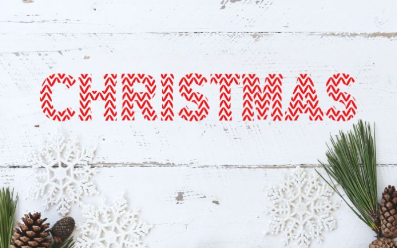 White snowy background with snow flakes and christmas decor elements and with a red color Christmas text on it