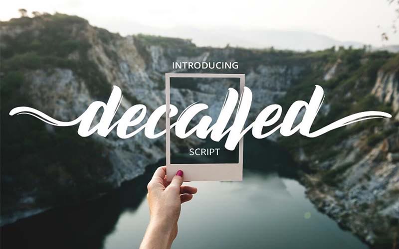 Decalled script banner with a person holding an instant picture and mountains and lake in the background
